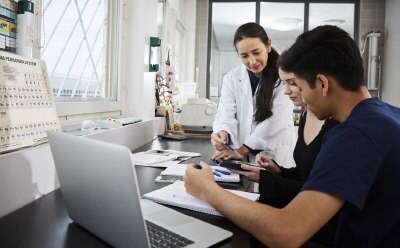 3 people on a desk discussing a scientific topic