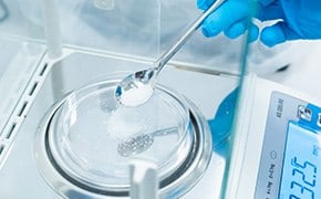 Ein Wissenschaftler mit blauen Handschuhen misst auf einer Digitalwaage ein wei&szlig;es Pulver ab, das PEG (Polyethylenglykole) und PEO (Polyethylenoxide) darstellt, die in verschiedenen wissenschaftlichen und industriellen Anwendungen eingesetzt werden.