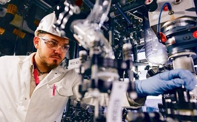 Manufacturing facility worker adjusting equipment, representing Merck's manufacturing workflow product offerings for medical device manufacturing.