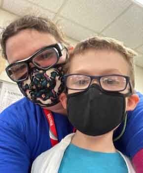 Allison and her son wear safety glasses and masks while taking a selfie.