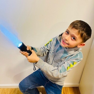 Léopol holds up a flashlight to imitate a light saber.