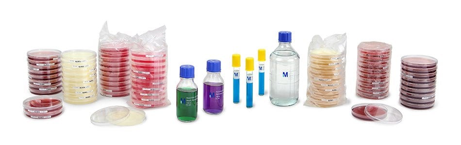 A collection of ready to use microbial culture media, including stacked Petri dishes in various colors, and several bottles of liquid culture media, arranged on a white background.